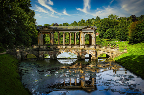 View of the beautiful Palladian Bridge, and water reflection, ancient architecture at the Prior Park Landscape Garden in Bath, Somerset, England, UK