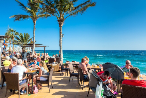 Tourists enjoy drinks and scenery at Cafe La Ola in Puerto del Carmen, Lanzarote island, The Canary Islands, Spain