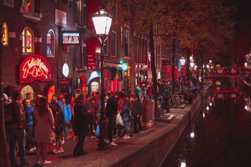 People walking around Amsterdam's Red-light district at night, it is one of the main tourist attractions in the city, Holland