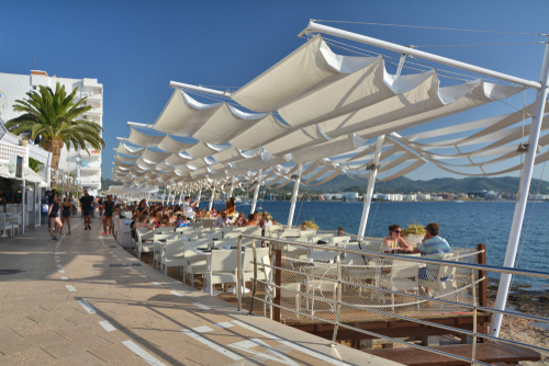 People sitting at Cafe del Mar in San Antonio de Portmany on Ibiza island, Balearic Islands, Spain. It is a famous seaside bar with the best Sunset views with music