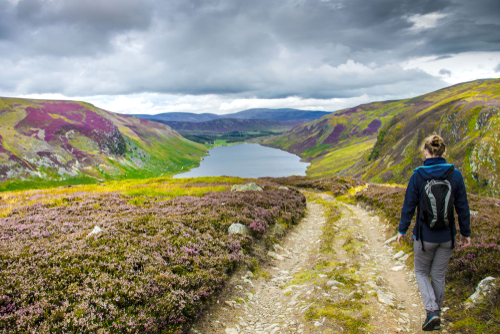 Woman hiker walking down from Cairn Lick to Loch Lee, Cairngorms National Park, Scotland, United Kingdom