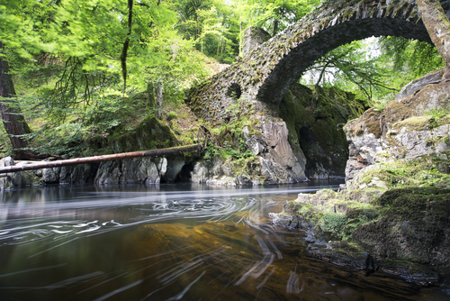 The Hermitage Bridge with river flowing through in long exposure, Cairngorms National Park, Perthshire, Scotland, UK