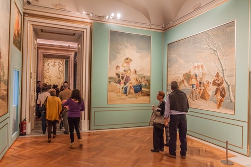 Interior view of people walking through one of the chambers at the Royal Palace (Palacio Real) in Madrid, Spain
