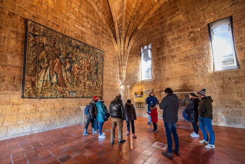 A tour guide showing tourists a tapestry on the way up to the top of the Segovia Cathedral bell tower, Segovia, Castilla y Leon, Spain