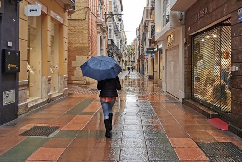 View of person using umbrella on the streets of Soho in Málaga on a rainy day, Andalusia, Spain