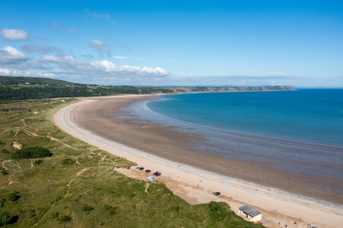 View of Oxwich Bay on the Gower Peninsula in Swansea, Wales, United Kingdom. A long sweeping sandy bay with a shallow water line with easy access by road from Swansea attracts visitors