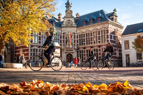 People riding on bikes in front of the Academiegebouw, Utrecht University Headquarters, in Utrecht, Holland, on an Autumn day