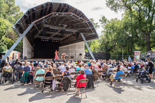 People enjoying a music performance in the open air theater at Vondelpark in Amsterdam, Holland