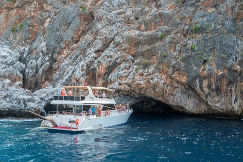 Cruise boat with tourists at the entrance to Phosphorus Sea Cave in Alanya, Antalya, Turkey