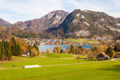 Beautiful view of alpine meadow, Fuschlsee lake, mountains and austrian town Fuschl am See on a sunny autumn day, near Salzburg, Austria