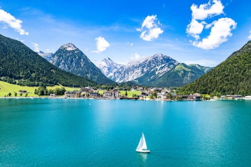 Amazing view of a sailboat in the middle of lake Achensee and the Alps in the background in Tyrol, Austria