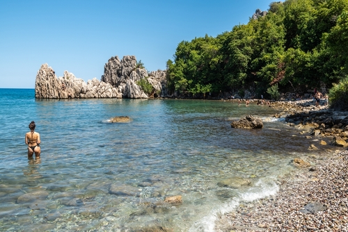 Beach in Olympos holiday hamlet in Antalya province of Turkey. View of the beach with people and cliffs in the background.