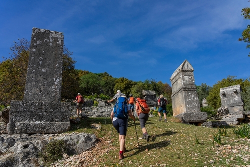 People hiking through the Lycian Sarcophagi and Fortress of Kalekoy in Antalya, Turkey