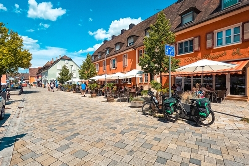 Charming cobblestone streets in the town square on a beautiful European Summer day. Vibrant colored buildings and tourists enjoying the outdoor cafe culture, Breisach, The Black Forest, Baden-Württemberg region of Germany