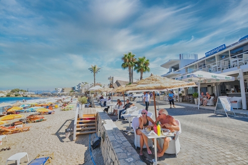 Beach with umbrellas and tourists in Hersonissos town, Island of Crete, Greece