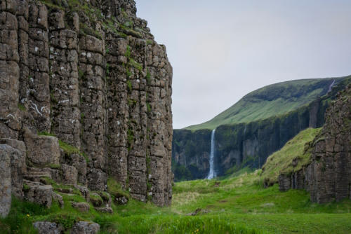 View through basalt columns to a waterfall at Dverghamrar or The Dwarf Cliffs in Landmannalaugar Reservation, Iceland