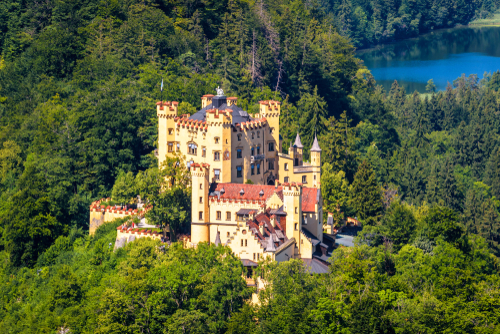 Aerial view of the old famous castle in forest by lake in Hohenschwangau area. Mountain landscape of Hohenschwangau castle in Summer near Fussen, Bavaria, Germany