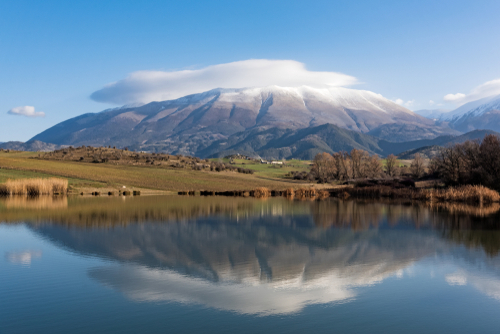 Distant view of Mount Olympus with clouds at the top and a reflection of the mountain in the lake, Mount Olympus is the highest mountain of Greece and the legend of the home of the ancient Greek gods, The Olympus Riviera, Greece