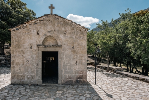Small Christian church high in the Psiloritis Mountains and surrounded by trees, on the trail to Rouvas Gorge near Rethymno, Island of Crete, Greece