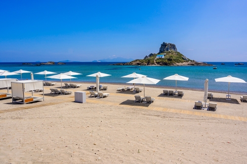 Deck chair and umbrellas on the beautiful Agios Stefanos Beach in front of the paradise Islet Kastri and paradise scenery on the coast of Kos Island, Dodecanse Islands, Greece