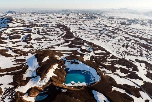 Aerial view of the Krafla Viti crater, this beautiful Crater is filled with blue water and surrounded by a geothermal area and colorful mountains, northeast Iceland