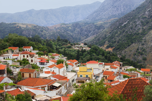 View of White houses with red rooftops in the mountains in the village of Argiroupolis, near Chania, Island of Crete, Greece