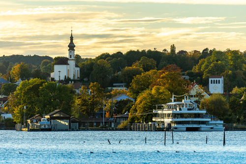 Evening atmosphere on Lake Starnberg in Kempfenhausen Percha, view of Starnberg and the harbor, ship and church in Bavaria, Germany