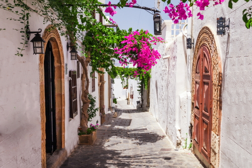 Narrow street in Lindos town on Rhodes island, Dodecanese, Greece, beautiful scenic old white houses with flowers