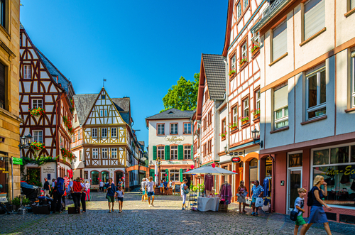 Traditional German houses of typical wooden facade fachwerk style and tourists people walking down cobblestone square in historical medieval town centre of Mainz, Rhine Valley, Rhineland-Palatinate, Germany