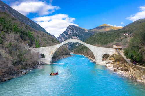 Spectacular view of the great arched stone bridge of Plaka over the beautiful blue waters Arachthos river, Tzoumerka, Greece