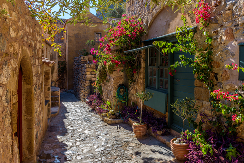 Traditional architecture with narrow stone street and a colorfull bougainvillea in the medieval castle of Monemvasia, Lakonia, The Peloponnese, Greece
