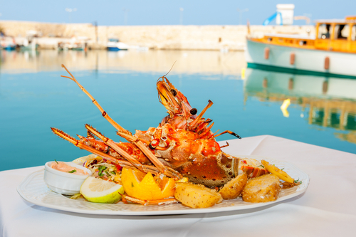 Lobster served with vegetables on white plate at a tavern in the old Venetian harbor of Rethymno, Island of Crete, Greece