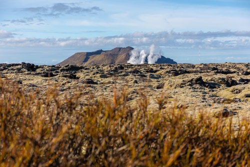 Volcanic landscape of Reykjanes peninsula with lava fields and gas steam of Svartsengi Geothermal Power Plant and Blue Lagoon, seen from road 43, Iceland