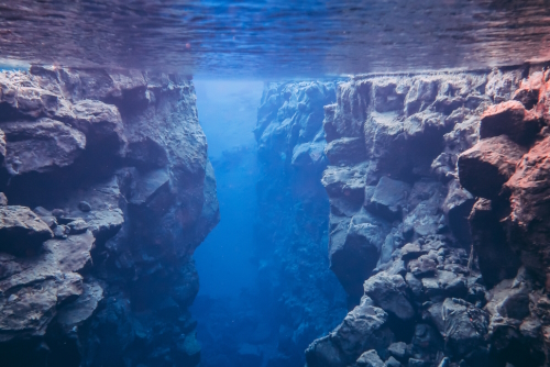 Silfra hall between two tectonic plates in National Park Thingvellir, Iceland, blue crystal clear pure water and colorful rocks stones volcanic lava formations underwater popular snorkeling diving site