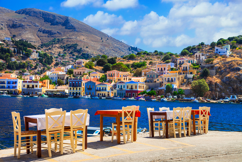 Traditional chairs and tables on a small street tavern on the harbor of a city on the Island of Symi, Dodecanese Islands, Greece