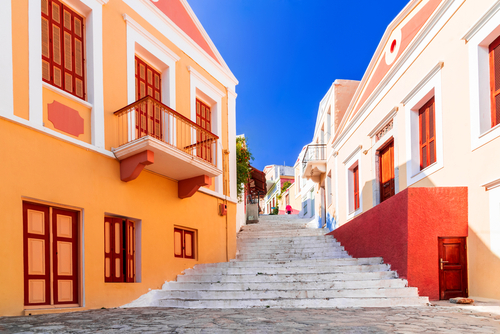 View of colorful houses and stairs on a street on the Island of Symi, Dodecanese Islands, Greece