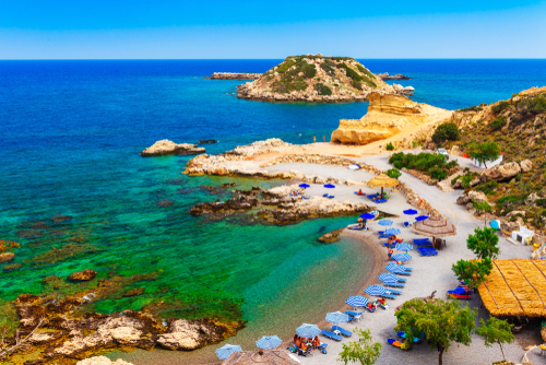 Aerial view of a picturesque beach with sand and clear blue water and the beach's facilities near Stegna and Archangelos villages on the Island of Rhodes, Greece