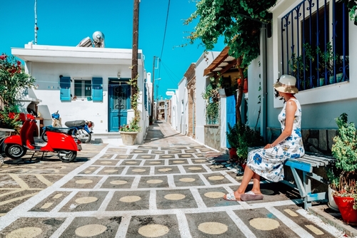 Woman in long dress sitting on bench in greek village Koskinou in Rhodes island in Greece