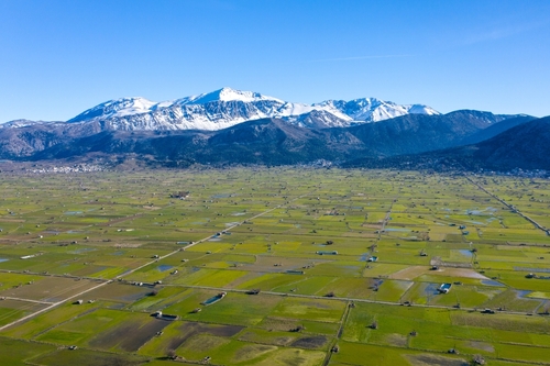 Contrast of green Lasithi Plateau and snowy peaks of Dikti Mountains, Lasithi, Crete Island, Greece