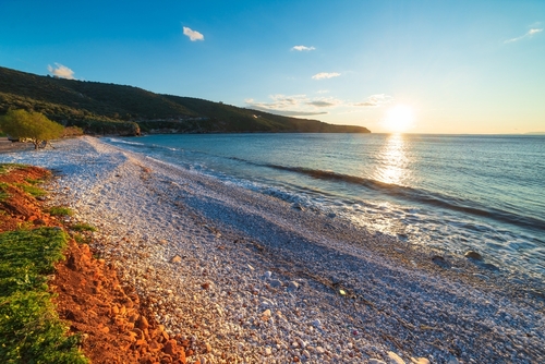 Sunset view beautiful beach and water bay in the greek spectacular coast line. Turquoise blue water unique white pebbles, the Mani Peninsula, The Peloponnese, Greece
