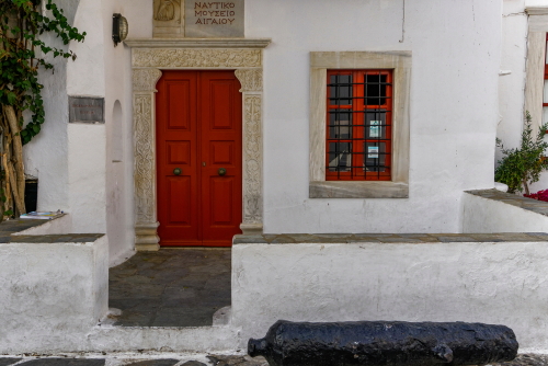 Aegean Maritime Museum exterior facade, Red door entrance to the nautical museum, displaying Greek maritime ship history and tradition, located at Mykonos Town on Mykonos Islands, Cyclades Islands, Greece