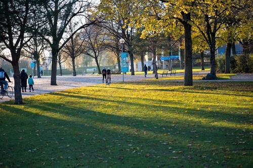 Walkers in the autumn light in the Olympiapark, Munich, Bavaria, Germany