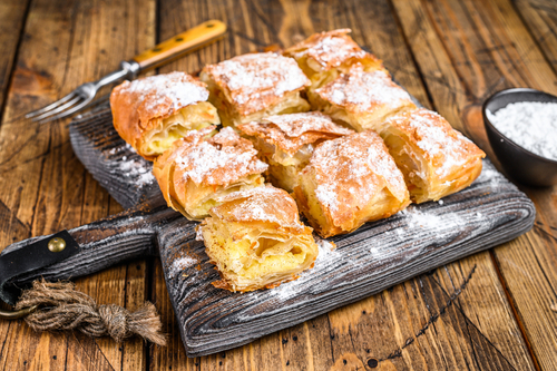 Thessaloniki's cream-filled bougatsas with phyllo dough and semolina custard cream, wooden background
