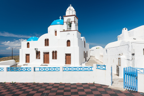White church with blue dome in the center of Manolas village on Thirasia island next to the Island of Santorini, Cyclades Islands, Greece