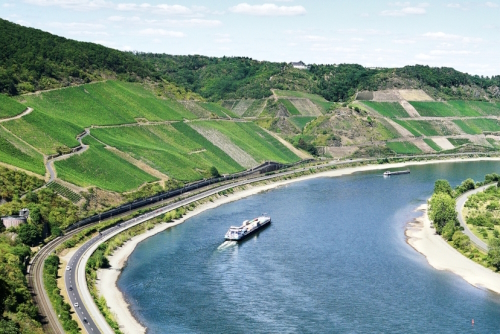 Elevated landscape view of the Rhine River and valley with steep vineyards famous for Riesling wine production. River barge travels on river, near Boppard in the Rhine Valley, Rhineland-Palatinate, Germany