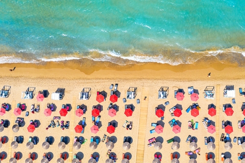 Top view of Banana beach and its facilities with beautiful turquoise water, sea waves and red umbrellas on Zakynthos Island, Ionian Islands, Greece