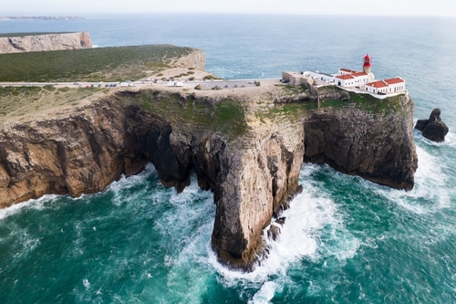 Algarve Coastline THUMB 03 - Dramatic view of the lighthouse on high cliffs and strong waves hitting the rock at Cape St. Vincent. Continental Europe's most South-western point, Sagres, Algarve, Portugal