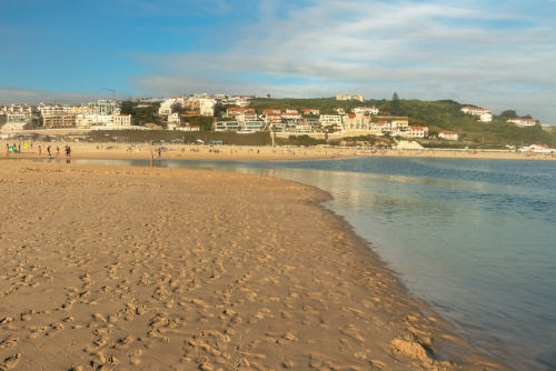 View of the beach at Foz do Arelho near Obidos in Portugal, from the sand with the village in the background, on a late summer afternoon