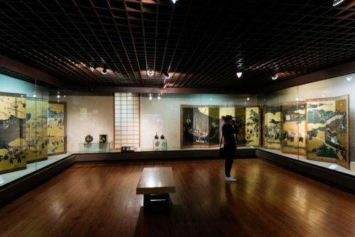 Female visitor taking a picture at Exhibition at the National Museum of Ancient Art, Lisbon, Portugal