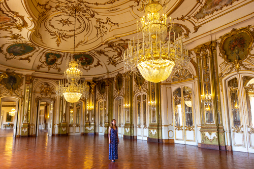 Tourist admires Rococo-style hall of the Queluz Palace, former residence of the royal family and tourist attraction on the outskirts of Lisbon, Portugal